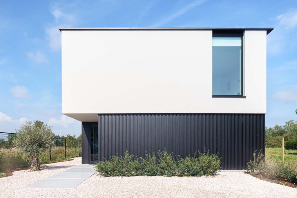 Woning met witte bovenverdieping en zwarte gevelbekleding.