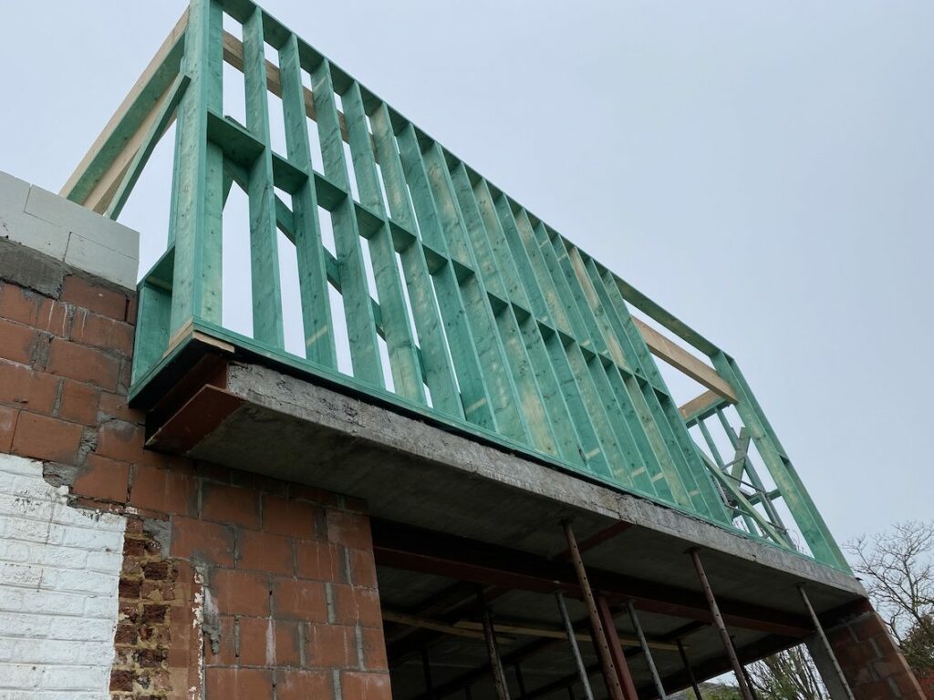 Houtskeletbouw woning met buitenframe op betonnen vloer en gemetselde onderbouw tijdens ruwbouwfase