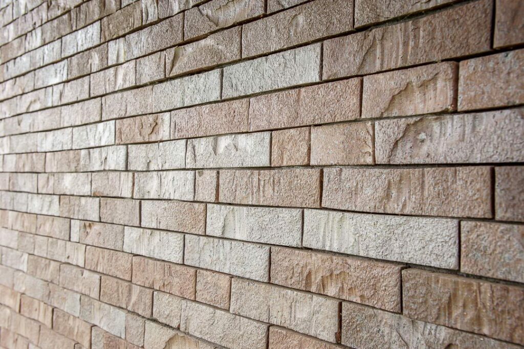Detail van een voegloze gevel met langwerpige bakstenen in lichte tinten