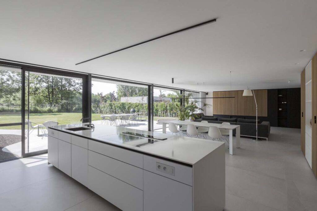 Open leefruimte met keuken afwerking en kookeiland met zicht op de tuin
