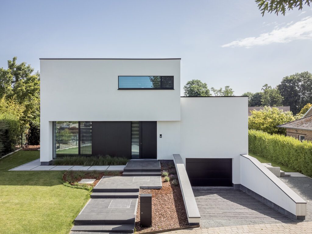 Witte moderne villa met zwart accent en inpandige garage in een groene omgeving