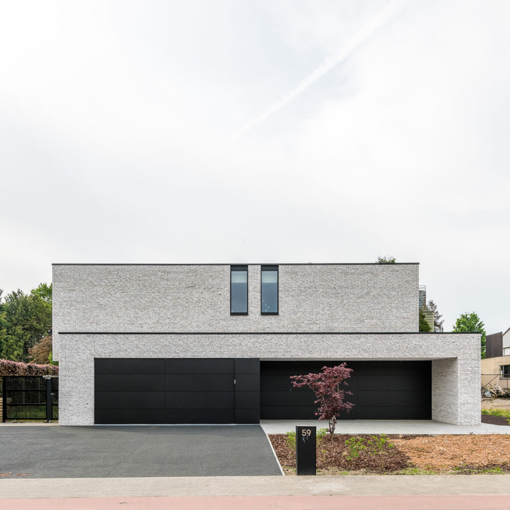 Strakke nieuwbouwwoning met witte gevelsteen en zwarte accenten.
