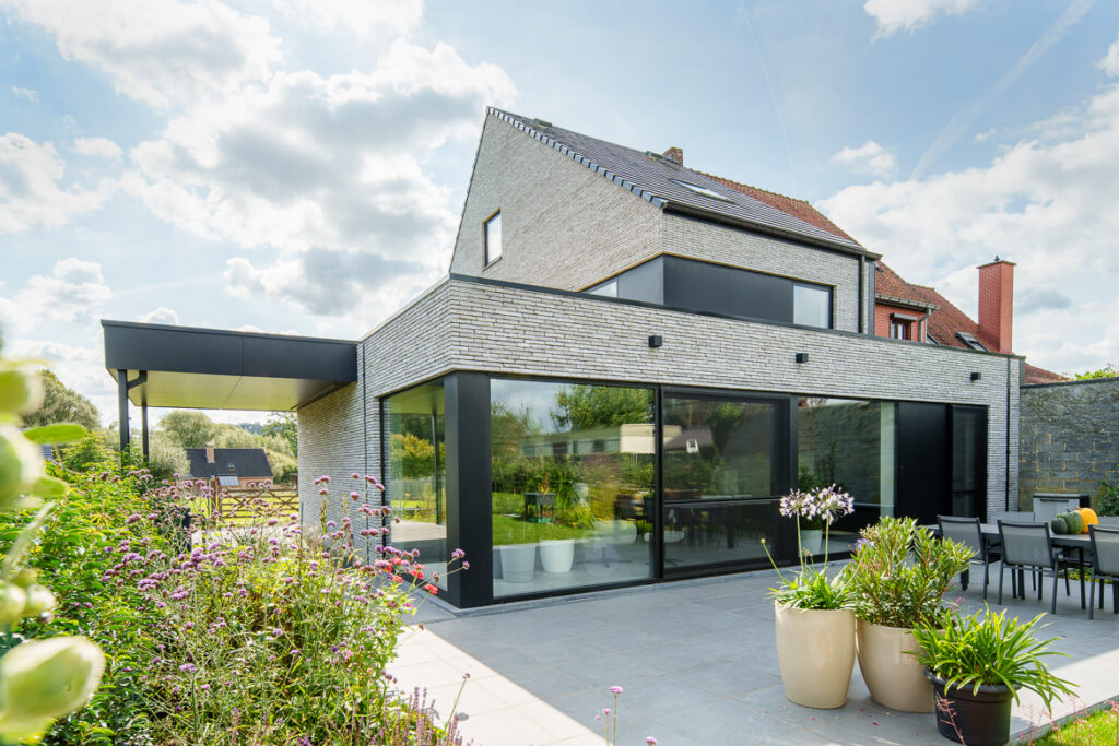 Strakke moderne aanbouw met grote raampartijen aan een gerenoveerde woning