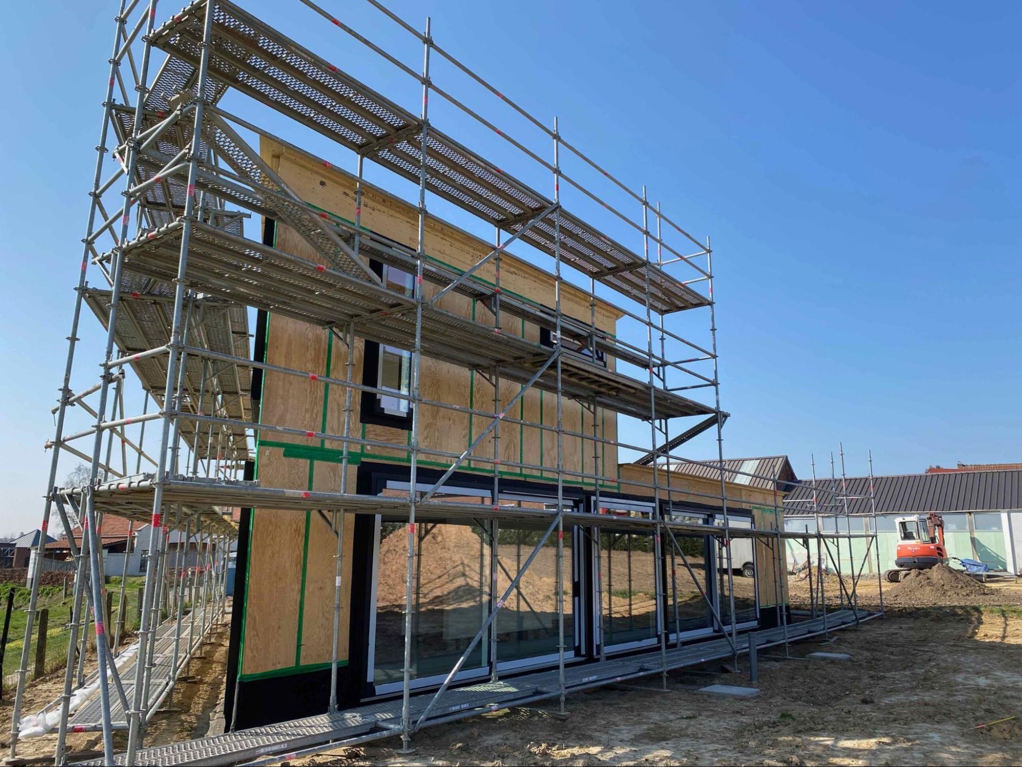 Woning in aanbouw met duurzame bouwmaterialen en houten structuur omringd door stellingen