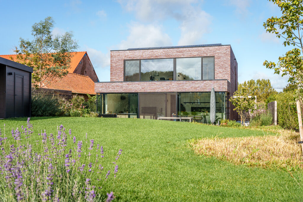 Moderne woning met afgewerkte gevel en grote glaspartijen als voorbeeld van waterdicht bouwen.