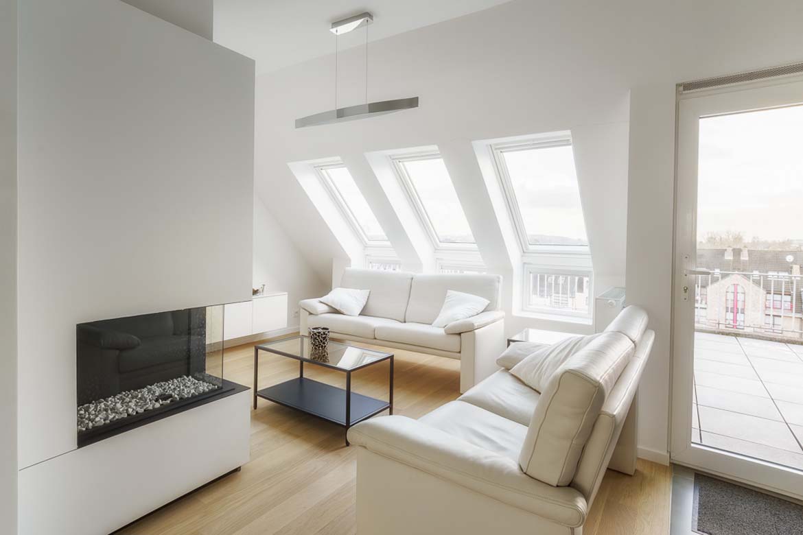 Lichte houten vloer in een witte woonkamer met zithoek en dakramen