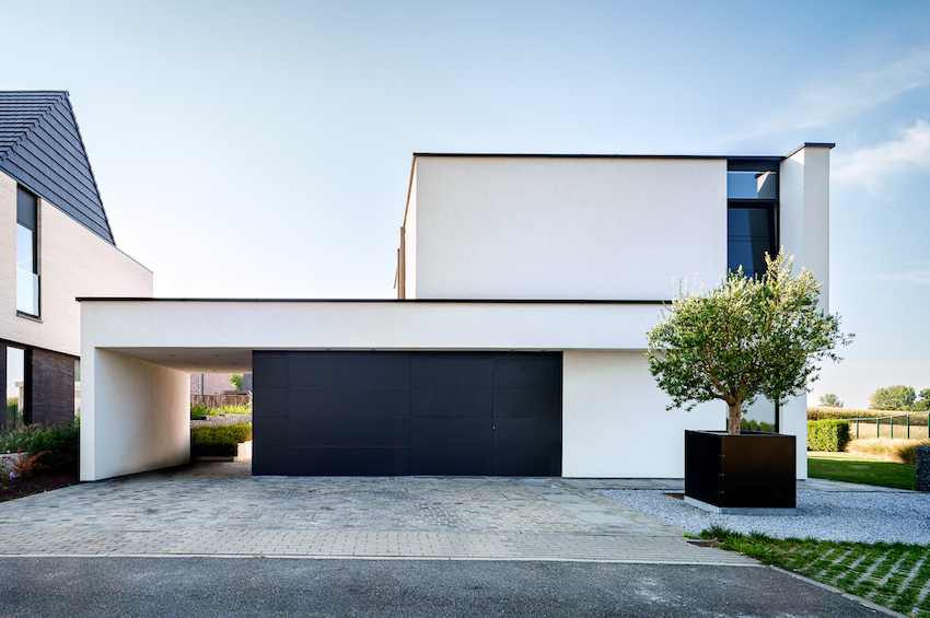 Strak afgewerkte moderne witte nieuwbouwwoning met carport en zwarte garagepoort
