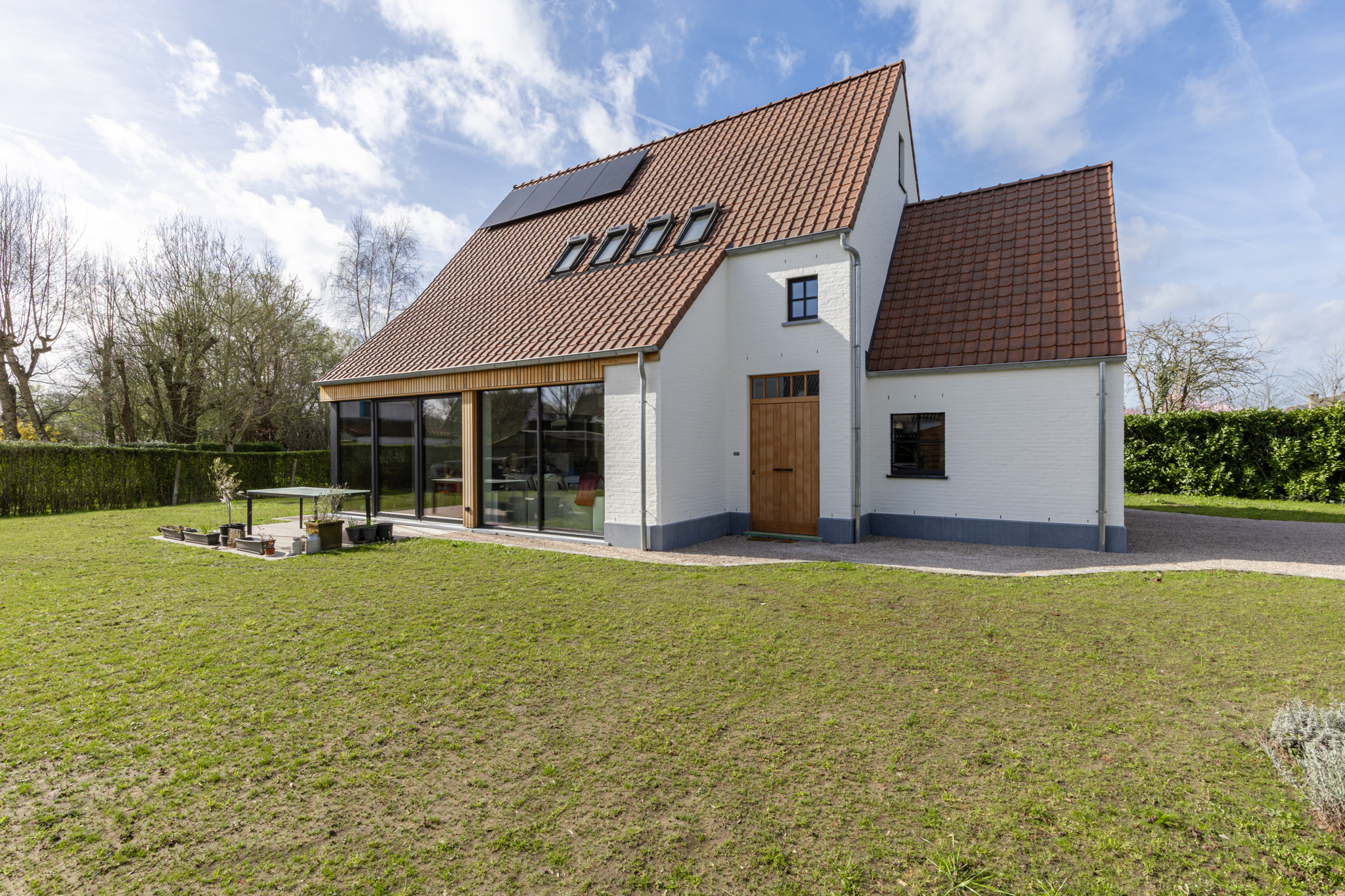 Afgewerkte landelijke woning met witgeschilderde gevel en houten bekleding na de oplevering, ontworpen door Sito Architecten.